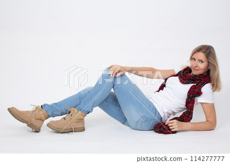 Adult beautiful slender woman in jeans and boots posing while lying in the studio. 114277777