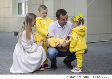Mom and dad show the children a newborn baby. A baby has appeared in the family. Meeting your newborn brother or sister. Family with children at the maternity hospital. Mom and dad show the children a newborn baby. A baby has appeared in the family. Meeting your newborn brother or sister. Family with children at the maternity hospital. 114277779