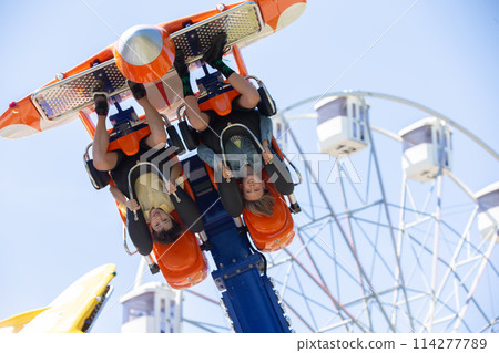 Teenagers ride head down on a carousel. Extreme rides in the park. 114277789