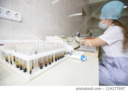 Medical test tubes with blood on the background of a blurred nurse. 114277897