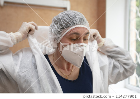 A doctor puts on a protective suit in a hospital during a coronavirus epidemic. A doctor puts on a protective suit in a hospital during a coronavirus epidemic. 114277901