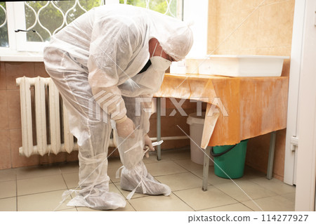 The doctor takes off his protective suit in the hospital during the coronavirus epidemic. 114277927
