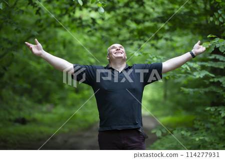A happy middle-aged man is walking in a beautiful forest. 114277931