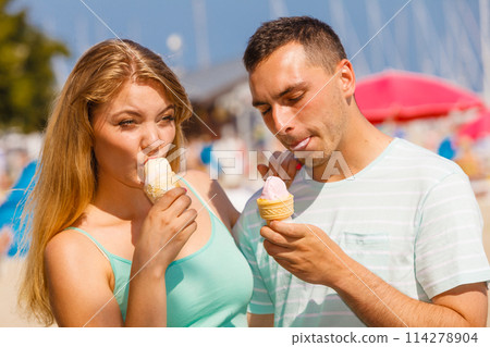 Man and woman eating ice cream on beach 114278904