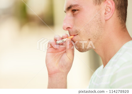 Adult man smoking cigarette outside 114278920