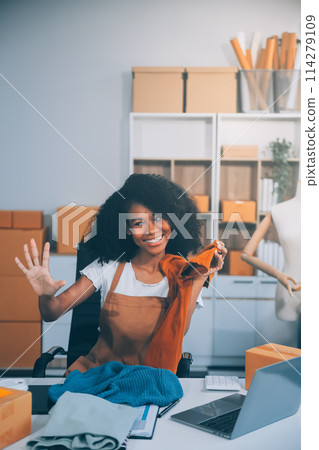 Fashion blogger concept, Young Asian women selling clothes on video streaming.Startup small business SME, using smartphone or tablet taking receive and checking in office 114279109