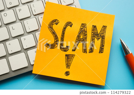 Keyboard and sticker with handwritten inscription scam on it. 114279322