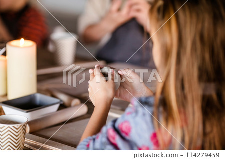 The girl is 7 years old blonde and does creative work with a ceramics studio and sculpts with clay 114279459