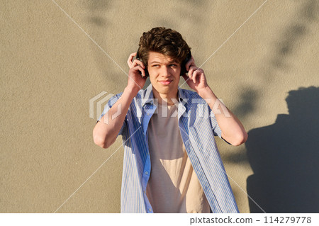 Young handsome male in wireless headphones listening to music Young handsome male in wireless headphones listening to music 114279778