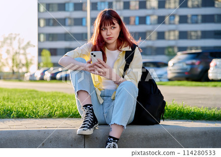 Young beautiful woman using smartphone, sitting on floor, urban style Young beautiful woman using smartphone, sitting on floor, urban style 114280533