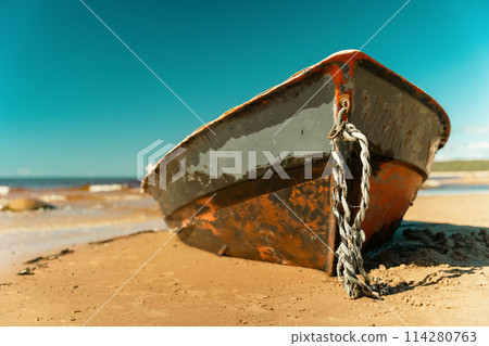 Old fishing boat rusting on sandy shore under sunny skies Old fishing boat rusting on sandy shore under sunny skies 114280763