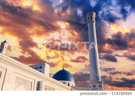 high white minaret and blue dome of modern Minor Mosque in Tashkent in Uzbekistan on background of beautiful sunset sky 114280984