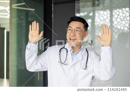 A joyful mature Asian doctor celebrates by dancing in his clinic, wearing a stethoscope and a lab coat, showing happiness and positivity in healthcare. A joyful mature Asian doctor celebrates by dancing in his clinic, wearing a stethoscope and a lab coat, showing happiness and positivity in healthcare. 114281495