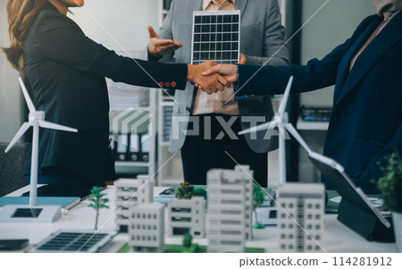 Two business executives, elegantly attired in suits, join hands in a gesture of unity, solidarity, and shared commitment towards a common goal or venture. 114281912
