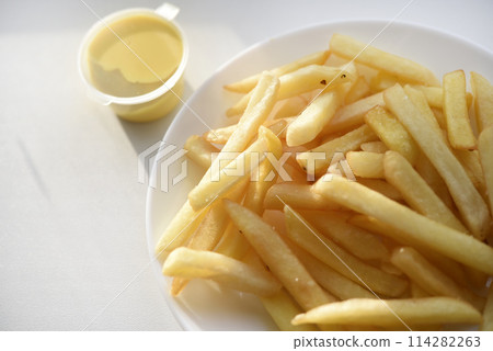 French fries on a white plate with sauce. Delicious fried crispy potatoes. 114282263