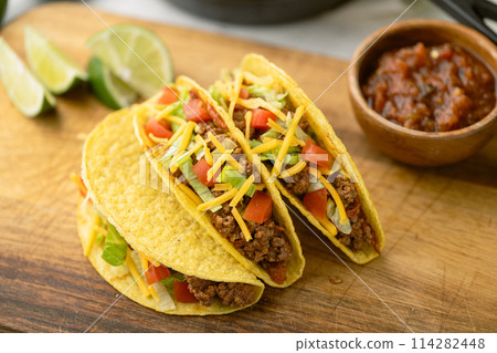 yellow hard shell tacos  on cutting board 114282448