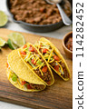 yellow hard shell tacos  on cutting board 114282452