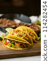 yellow hard shell tacos  on cutting board 114282454