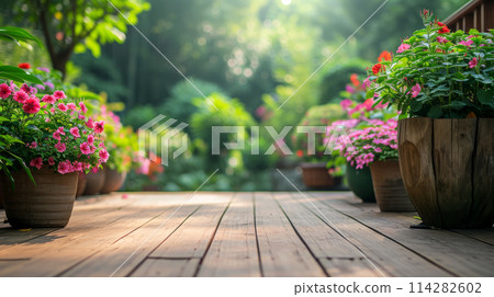 A beautifully arranged garden deck bathed in the soft, ethereal light of morning sun, wooden and well-maintained deck is adorned with array of potted flowering plants that burst with vibrant colors 114282602