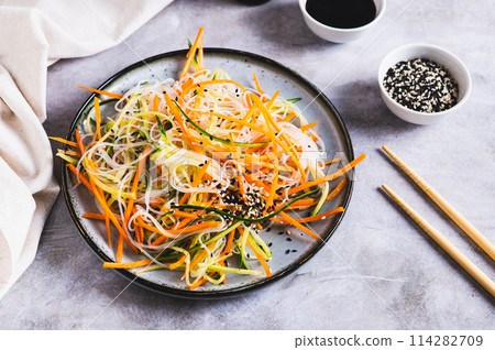 Funchoza salad with fresh cucumber and Korean carrots on a plate on the table Funchoza salad with fresh cucumber and Korean carrots on a plate on the table 114282709