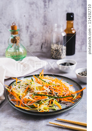 Appetizing salad of funchose, carrots, cucumber and sesame on a plate vertical view Appetizing salad of funchose, carrots, cucumber and sesame on a plate vertical view 114282710