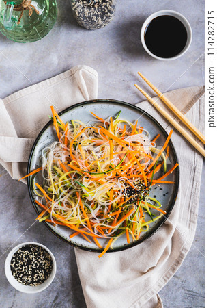 Funchoza salad with fresh cucumber and Korean carrots on a plate top and vertical view Funchoza salad with fresh cucumber and Korean carrots on a plate top and vertical view 114282715