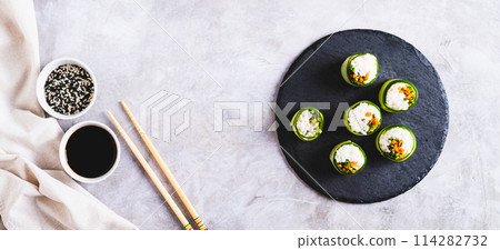 Vegetarian sushi rice, carrots and green onions wrapped in cucumber top view web banner 114282732