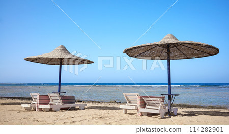 Beautiful sandy beach with sun loungers and umbrellas, Marsa Alam region, Egypt. Beautiful sandy beach with sun loungers and umbrellas, Marsa Alam region, Egypt. 114282901