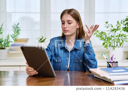 Teenage female student at home looking talking in web camera of digital tablet Teenage female student at home looking talking in web camera of digital tablet 114283436