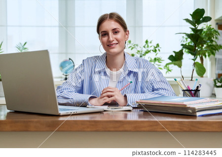 High school, college student smiling young female sitting at desk with computer 114283445