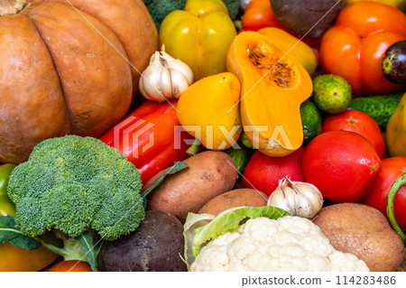Various vegetables are laid out on a wooden table. Large assortment of vegetables food. pumpkin cabbage broccoli pepper tomatoes carrots and others 114283486