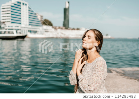 A woman is sitting in the water wearing a white dress. The water is calm and blue. The woman is enjoying the moment and taking in the beauty of the scene. 114283488