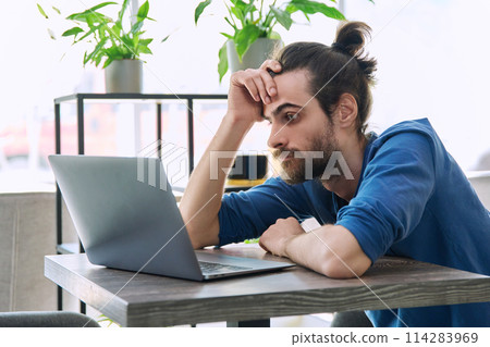 Surprised excited overjoyed young handsome man looking at laptop sitting in cafe 114283969