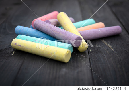 Colorful pieces of chalk on a wooden texture background Colorful pieces of chalk on a wooden texture background 114284144
