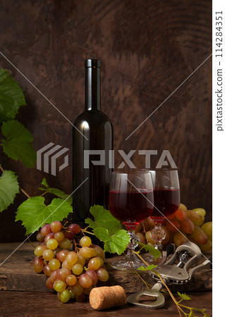Still life with glasses of red wine and grapes on vintage wooden background.. Still life with glasses of red wine and grapes on vintage wooden background.. 114284351