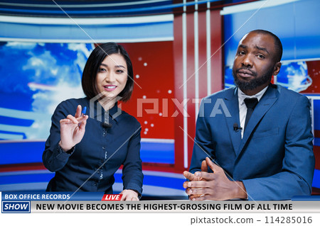 Reporters present new movie breaking charts, news report analysts talking about film bringing down box office records. Team of diverse journalists reading headlines, daily events. Reporters present new movie breaking charts, news report analysts talking about film bringing down box office records. Team of diverse journalists reading headlines, daily events. 114285016