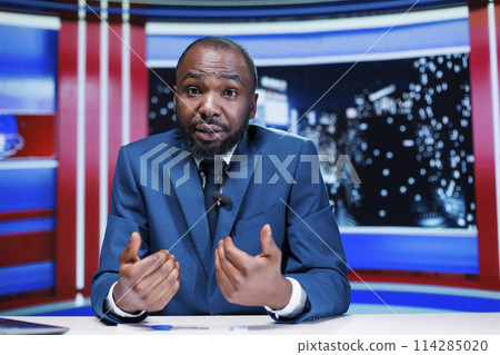 TV newscaster presenting news on live transmission channel, using daily headlines to create events reportage newscast. Media presenter working in television industry, night show. TV newscaster presenting news on live transmission channel, using daily headlines to create events reportage newscast. Media presenter working in television industry, night show. 114285020