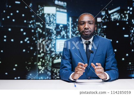 Anchorman working on live broadcast to discuss about latest events during night show segment, covering important topics. African american news reporter creating newscast with headlines. Anchorman working on live broadcast to discuss about latest events during night show segment, covering important topics. African american news reporter creating newscast with headlines. 114285059