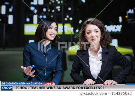 Genious teacher winning award for showing innovation in education system, diverse presenters talk about huge achievement on live television channel. Newscasters team reveal success of professor. 114285083
