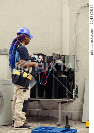 Trained serviceman for routine condenser maintenance, assembling set of freon barometer starting work. Certified repairman reading refrigerant pressure in hvac system cooling tank 114285085