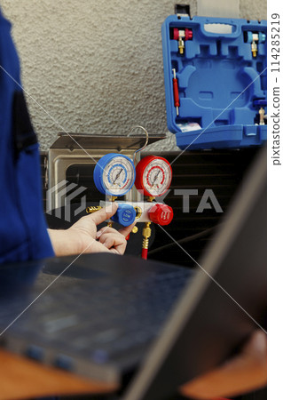 Licensed serviceman calibrating set of barometer meters during comissioned condenser analysis. Experienced professional looking for potential high pressure in hvac system cooling system, close up 114285219