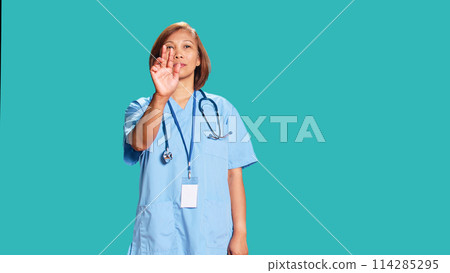 Nurse doing swiping hand motions, remotely controlling tactile screen. Healthcare specialist working in high-tech futuristic modern medical clinic, isolated over blue studio background Nurse doing swiping hand motions, remotely controlling tactile screen. Healthcare specialist working in high-tech futuristic modern medical clinic, isolated over blue studio background 114285295