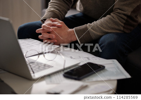 Clasped hands of man checking data Clasped hands of man checking data 114285569