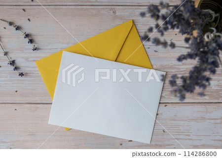 Flat lay composition of white paper greeting card on envelope with dry lavender flowers. Copy space template mock up. Top view. Concept of Wedding invitation postcard. Business advertisement 114286800
