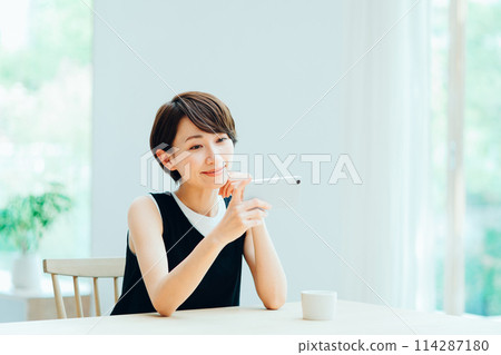 A woman who operates a smartphone in the living room. 114287180