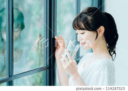 女人早上在窗邊喝水。 114287323