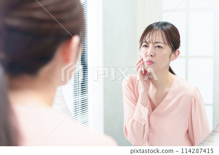 Woman looking in the mirror, skin trouble, worries 114287415