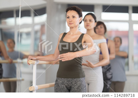 Group of amateurs of different ages practice ballet moves in classical dance class Group of amateurs of different ages practice ballet moves in classical dance class 114289718