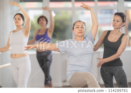 Ballet lesson for amateurs - choreographer teaches women of different ages different ballet steps in studio 114289781