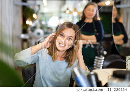 Delighted female client sitting in hairdressing chair after haircut 114289834